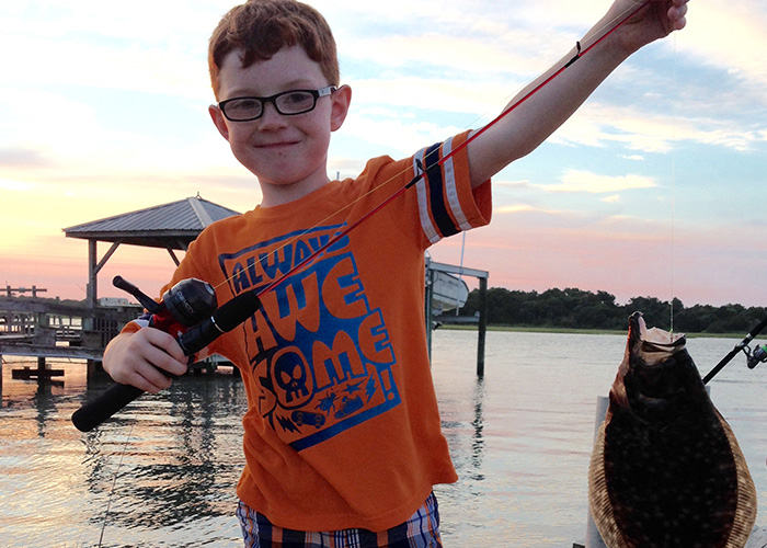 A boy reels in a fish from Holden Beach Peir